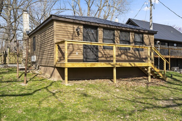 rear view of property featuring a deck and a lawn