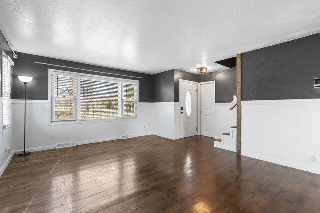 spare room featuring a textured ceiling and dark hardwood / wood-style flooring