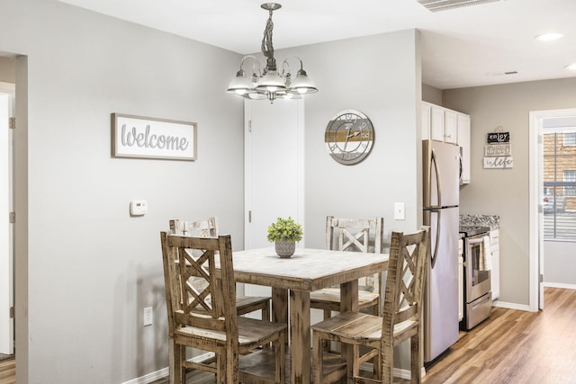 dining space featuring a notable chandelier and light wood-type flooring