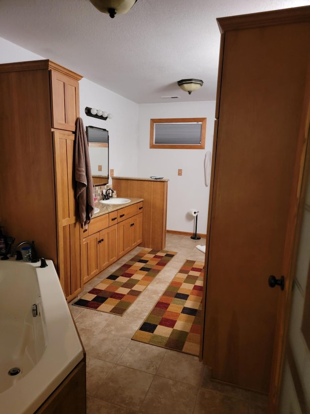 bathroom featuring vanity, tile patterned flooring, a textured ceiling, and a tub