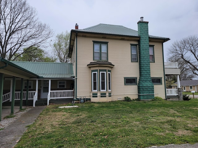 rear view of house featuring a yard and covered porch