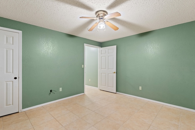 empty room with ceiling fan, light tile patterned floors, and a textured ceiling