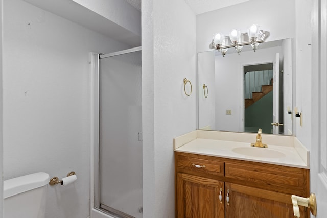 bathroom with a textured ceiling, a shower with shower door, vanity, and toilet