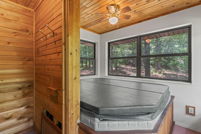 interior space featuring ceiling fan, wood walls, a hot tub, and wood ceiling