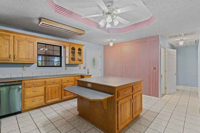 kitchen featuring ceiling fan, dishwasher, a textured ceiling, and a center island