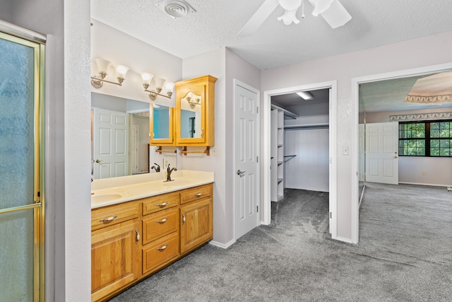 bathroom with ceiling fan, a shower with shower door, vanity, and a textured ceiling