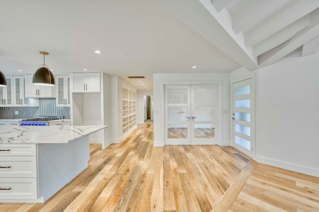 kitchen featuring white cabinets, light stone countertops, hanging light fixtures, and light hardwood / wood-style floors