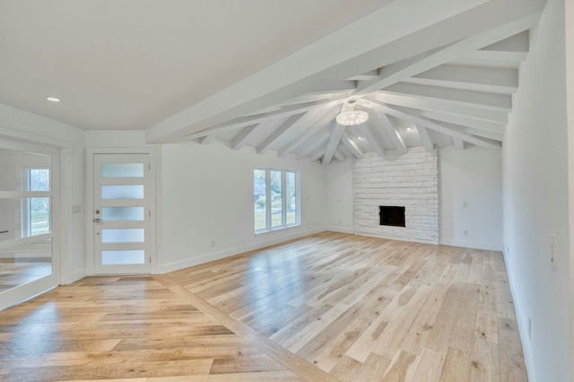 unfurnished living room with vaulted ceiling with beams, a stone fireplace, and light hardwood / wood-style flooring