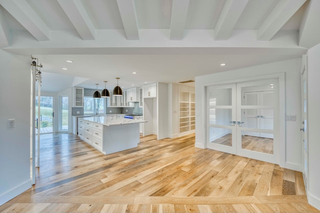 kitchen featuring a barn door, hanging light fixtures, a kitchen island, and white cabinetry