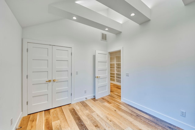 unfurnished bedroom with lofted ceiling, a closet, and light wood-type flooring