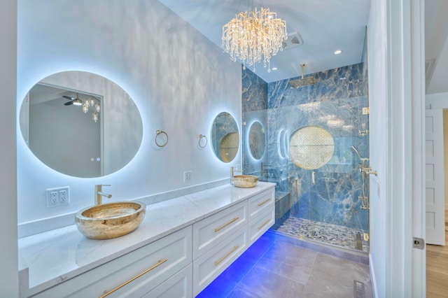 bathroom with a notable chandelier, tiled shower, and vanity