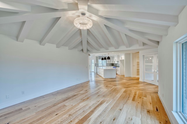 unfurnished living room with lofted ceiling with beams, light hardwood / wood-style floors, and a healthy amount of sunlight