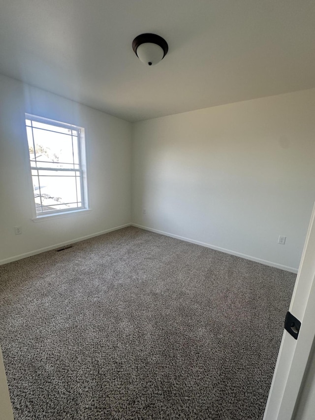 spare room with carpet, visible vents, and baseboards