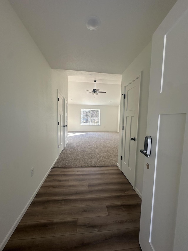 hall featuring dark wood-type flooring and baseboards