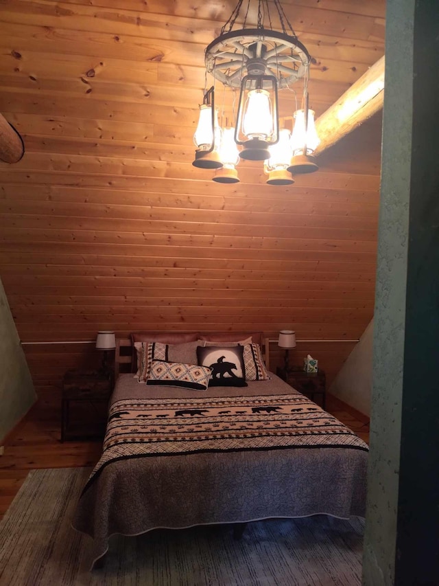 bedroom with wood walls, wood-type flooring, and a notable chandelier