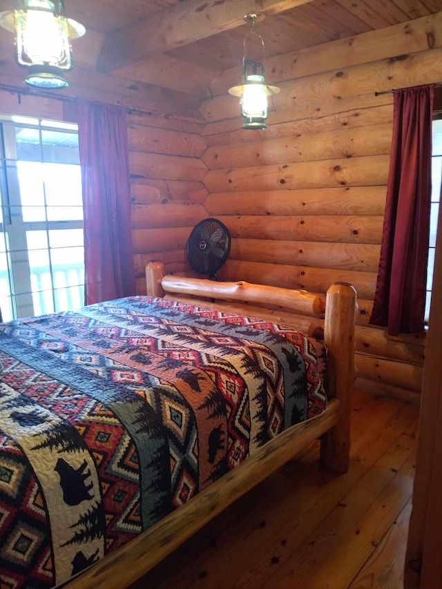 bedroom with hardwood / wood-style flooring, beam ceiling, and log walls