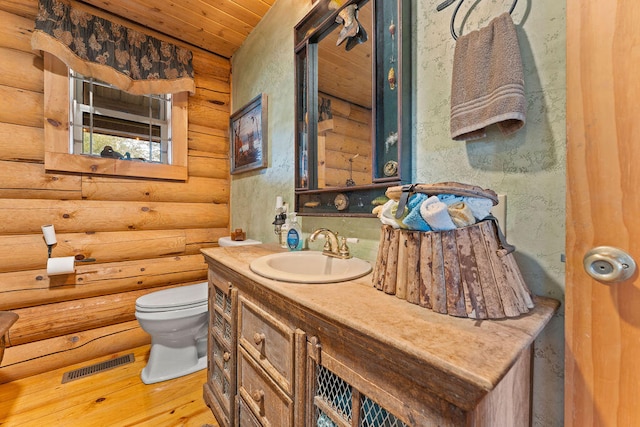 bathroom with rustic walls, toilet, wooden ceiling, hardwood / wood-style floors, and vanity