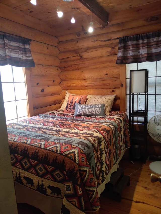 bedroom with log walls, wooden ceiling, beamed ceiling, and hardwood / wood-style floors