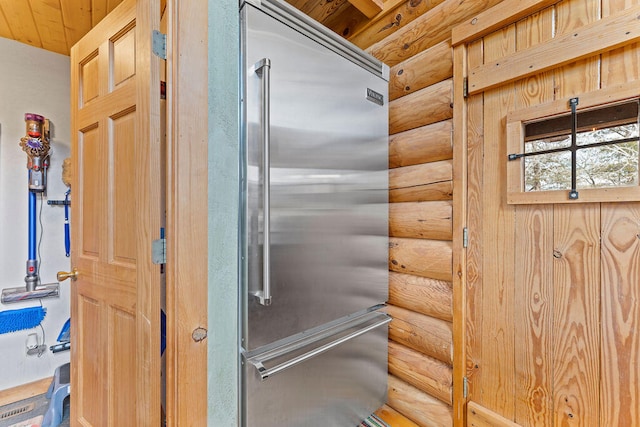 room details featuring log walls, built in refrigerator, and wood ceiling