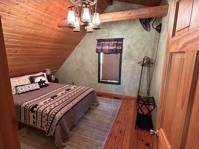 bedroom with hardwood / wood-style flooring, vaulted ceiling, and an inviting chandelier