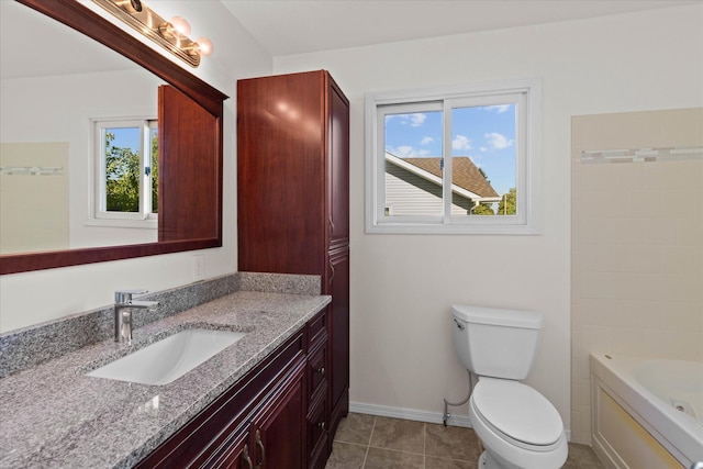 bathroom with a bathing tub, vanity, toilet, and a healthy amount of sunlight