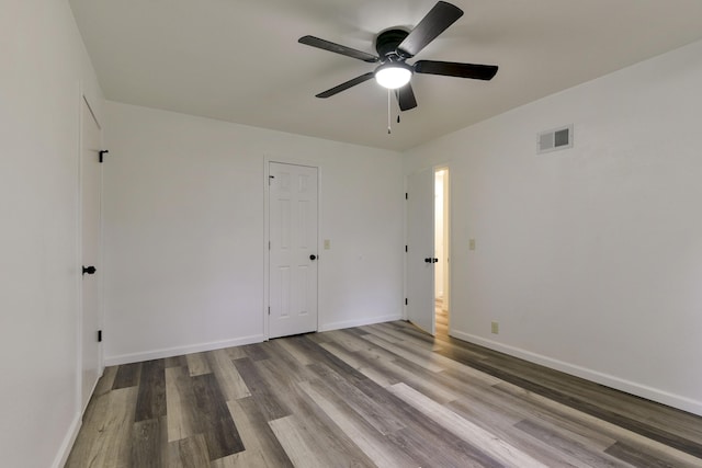 unfurnished bedroom featuring visible vents, baseboards, a ceiling fan, and wood finished floors
