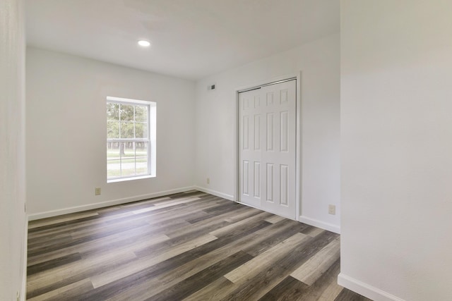 unfurnished bedroom featuring recessed lighting, wood finished floors, visible vents, a closet, and baseboards