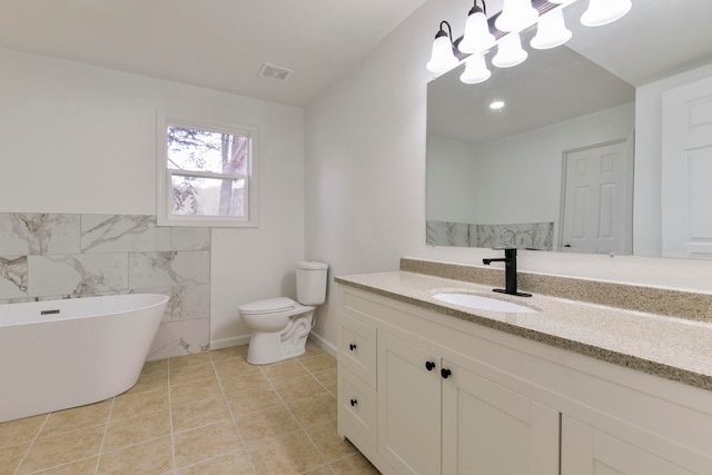 bathroom with vanity, toilet, a tub to relax in, tile walls, and tile patterned flooring