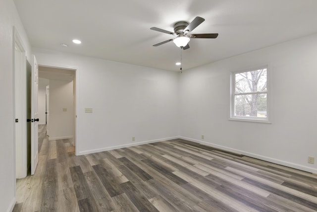 empty room with recessed lighting, wood finished floors, a ceiling fan, and baseboards