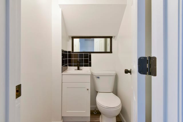 bathroom featuring hardwood / wood-style floors, vanity, decorative backsplash, and toilet