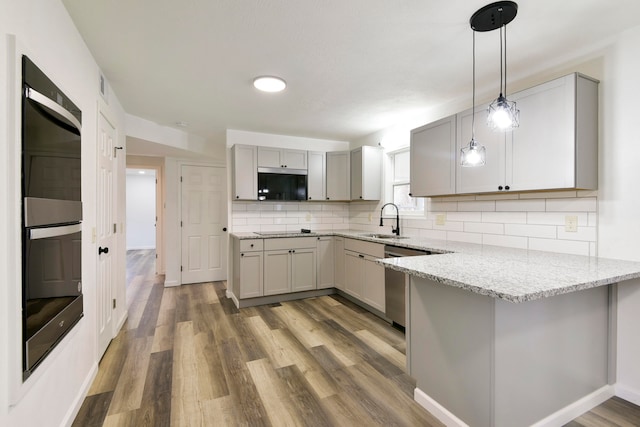 kitchen with pendant lighting, sink, gray cabinets, light stone countertops, and hardwood / wood-style floors