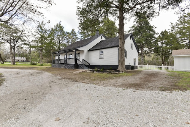 view of front of house featuring a porch, driveway, fence, and roof with shingles