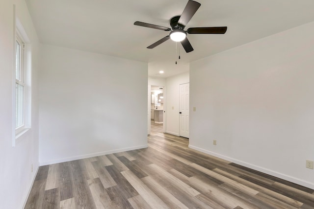 unfurnished room featuring ceiling fan, hardwood / wood-style flooring, and a healthy amount of sunlight