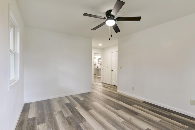 empty room with recessed lighting, wood finished floors, a ceiling fan, and baseboards