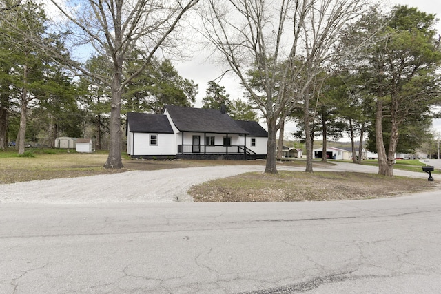 tudor home with driveway, an outbuilding, a porch, and a storage unit
