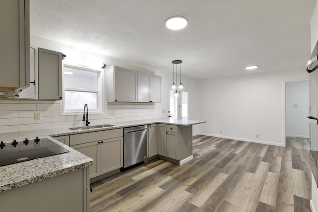 kitchen with a peninsula, black electric cooktop, a sink, backsplash, and dishwasher