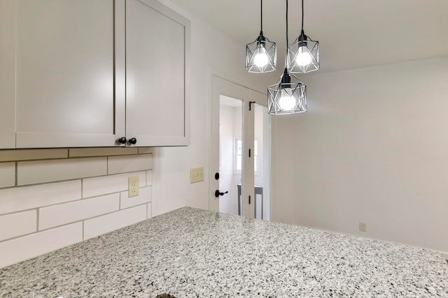 details with light stone counters, hanging light fixtures, and white cabinets