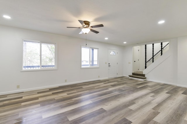 unfurnished living room featuring stairway, wood finished floors, ceiling fan, baseboards, and recessed lighting