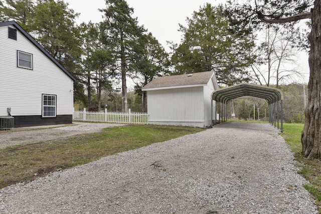view of property exterior featuring central AC, a detached carport, gravel driveway, and fence