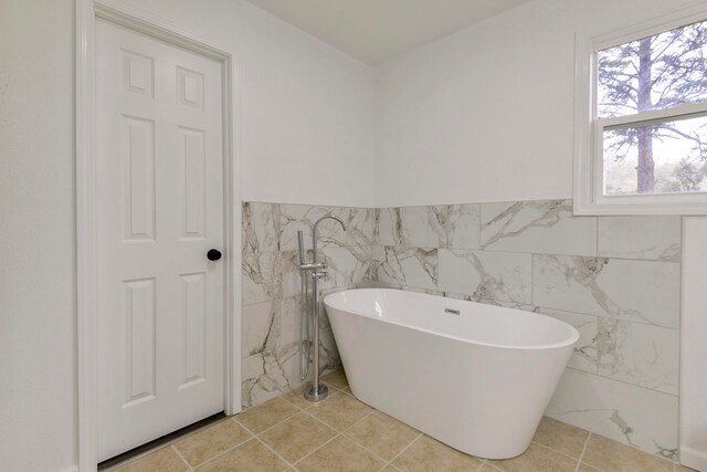 bathroom with tile patterned floors, a bathing tub, and tile walls