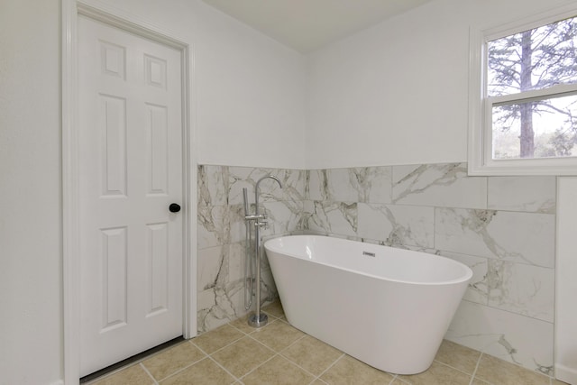 bathroom featuring wainscoting, a soaking tub, and tile walls