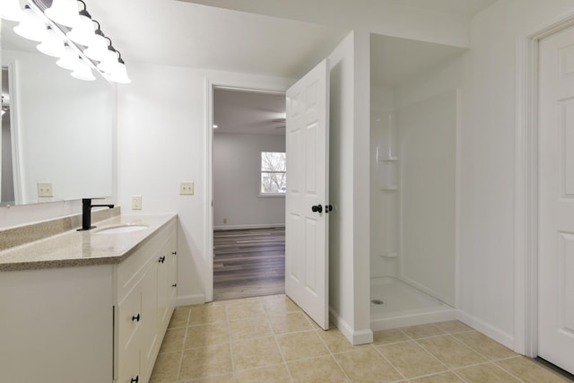 bathroom featuring walk in shower, baseboards, tile patterned flooring, and vanity