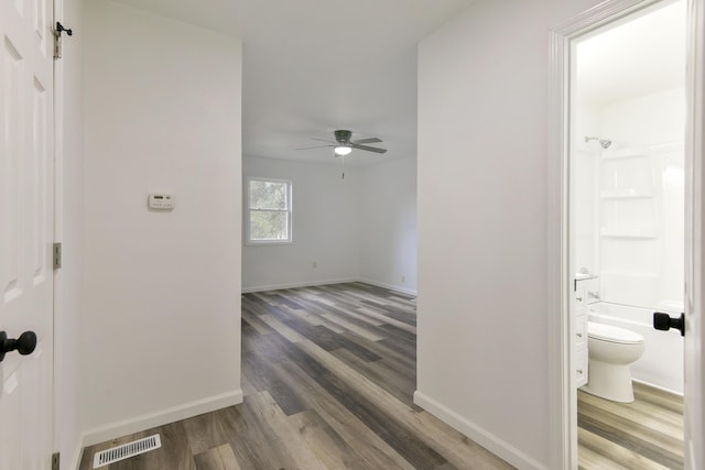 hallway with baseboards, wood finished floors, and visible vents