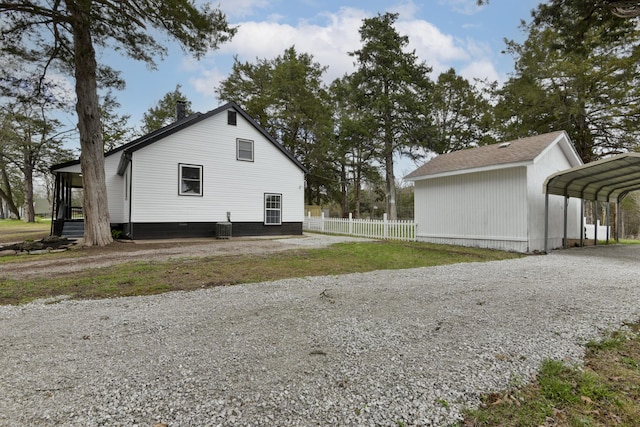 view of side of property with a carport, driveway, fence, and cooling unit
