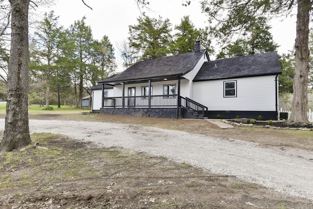 view of front of home with a chimney, a porch, and a shingled roof