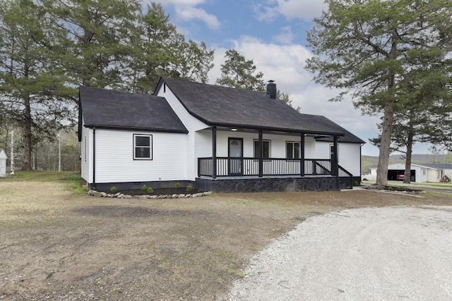 view of front of house with a porch, crawl space, a shingled roof, and a chimney