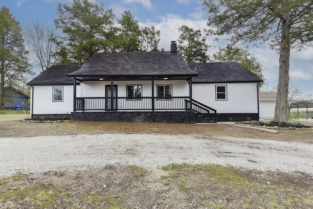view of front of home with a shingled roof, a chimney, and covered porch