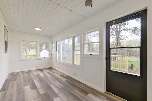 unfurnished sunroom featuring ceiling fan, wood ceiling, and plenty of natural light