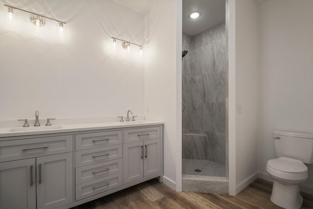 bathroom featuring a tile shower, vanity, hardwood / wood-style floors, and toilet