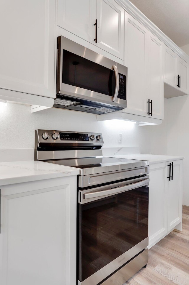 000 State Route Jj, West Plains, MO 65775 - kitchen with light stone countertops, white cabinetry, light wood finished floors, and stainless steel appliances